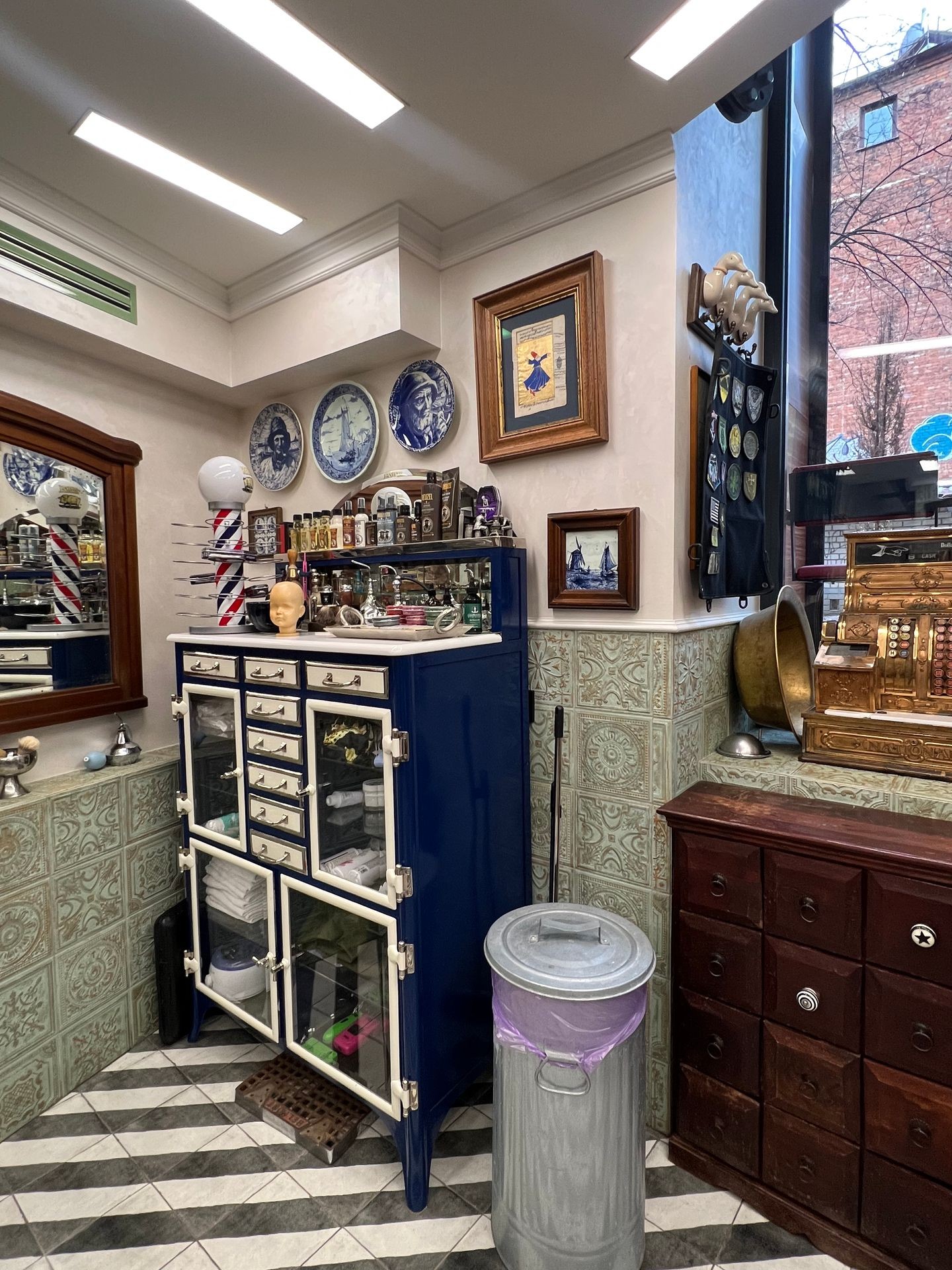 Vintage interior with a blue cabinet, decorative plates, and framed pictures on tiled walls.
