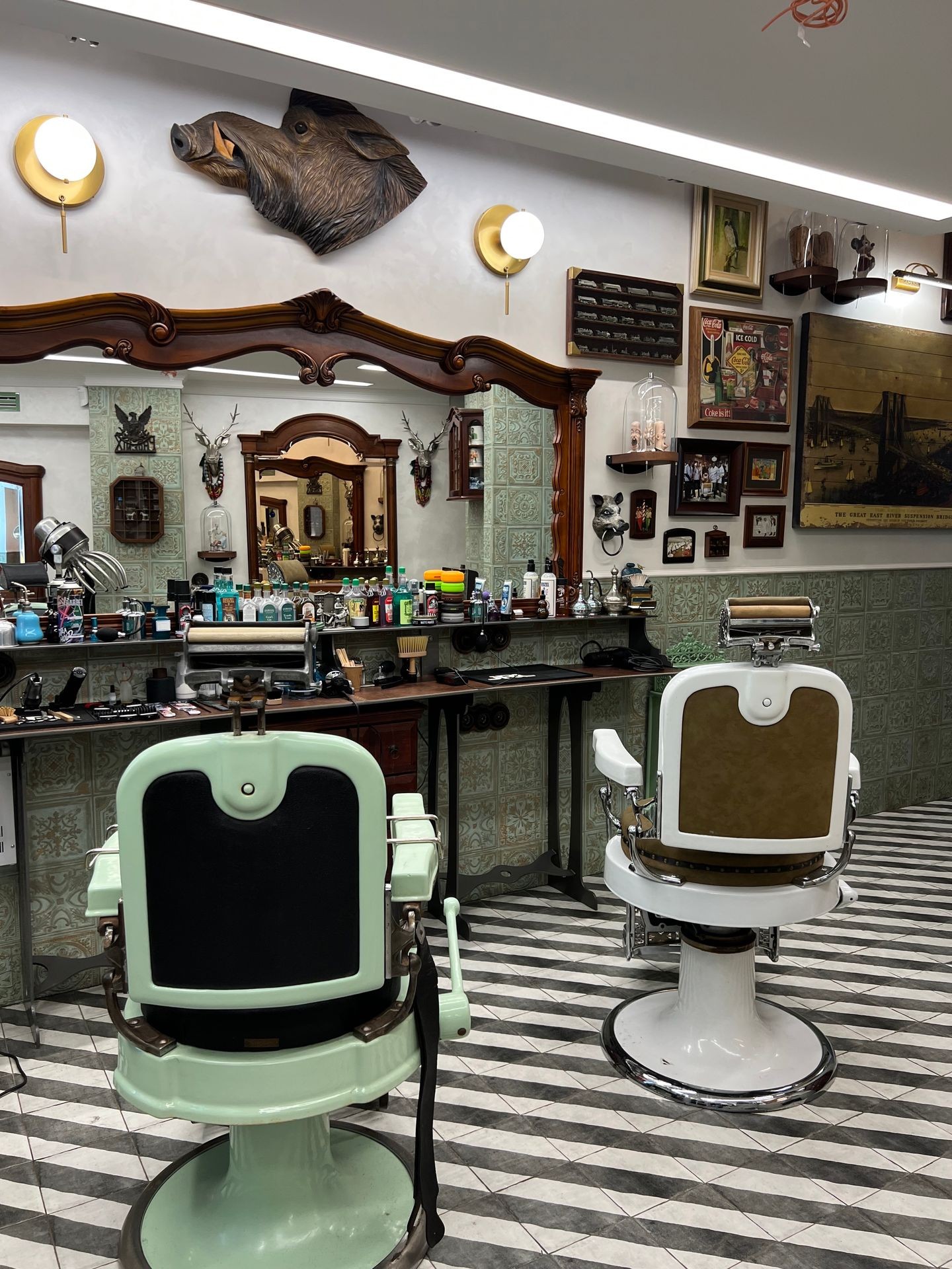 Vintage barbershop interior with classic barber chairs and a boar head on the wall.