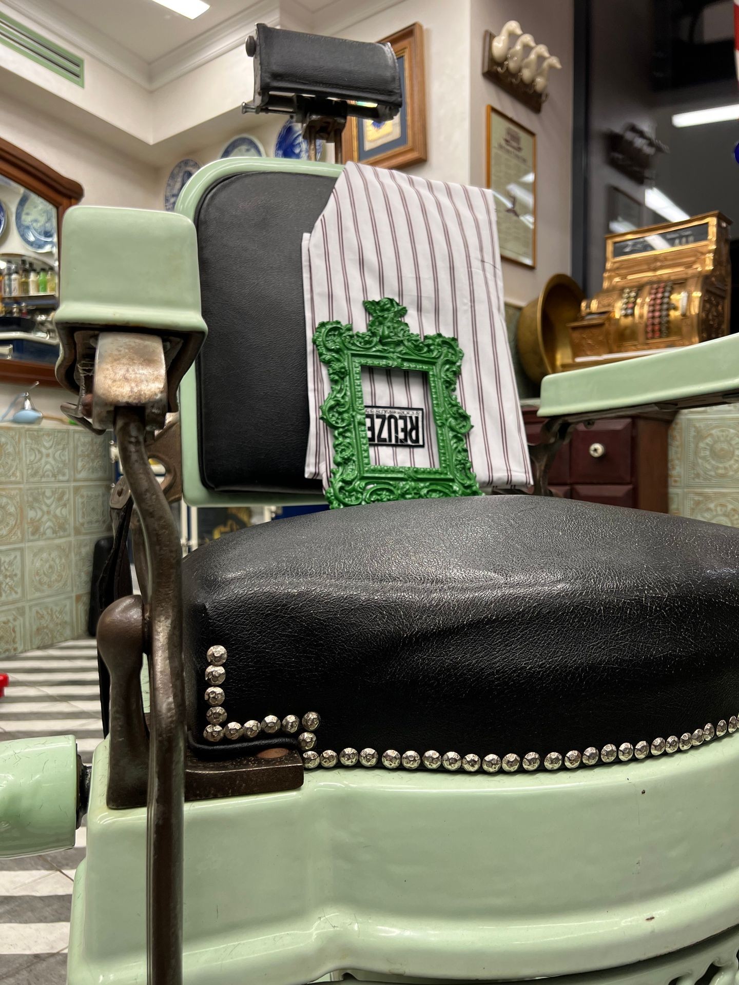 Vintage barber chair with decorative frame and striped fabric in a shop setting.